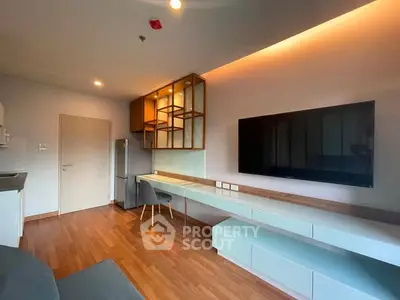 Modern living room with sleek wooden flooring, large TV, and stylish shelving.
