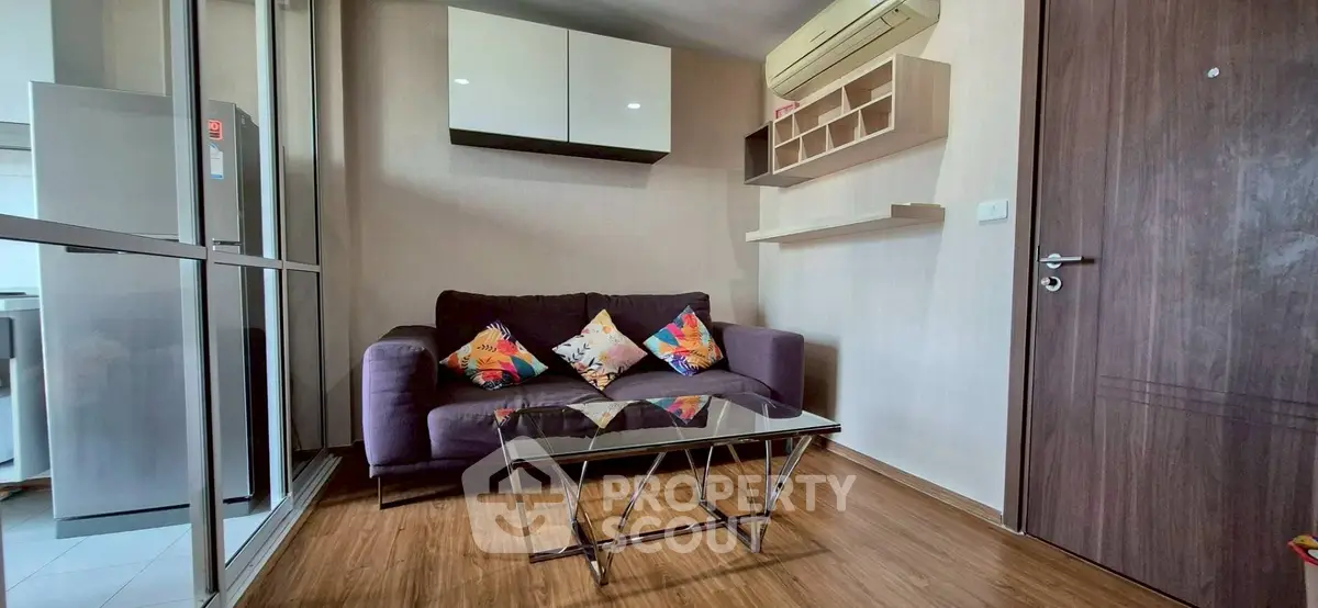 Modern living room with glass table and colorful cushions in cozy apartment.