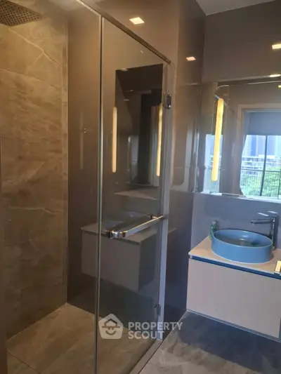 Modern bathroom with glass shower and stylish blue basin