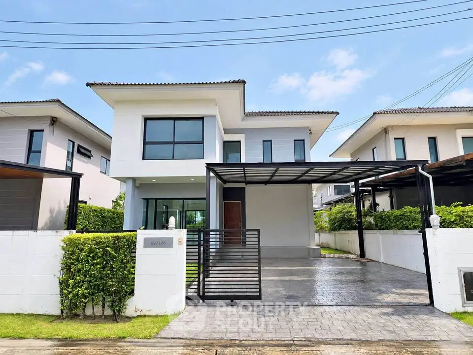Modern two-story house with spacious driveway and sleek design in a suburban neighborhood.
