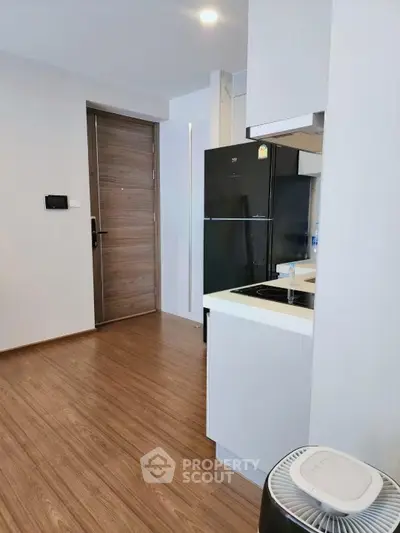 Modern kitchen with sleek appliances and wooden flooring in a stylish apartment.