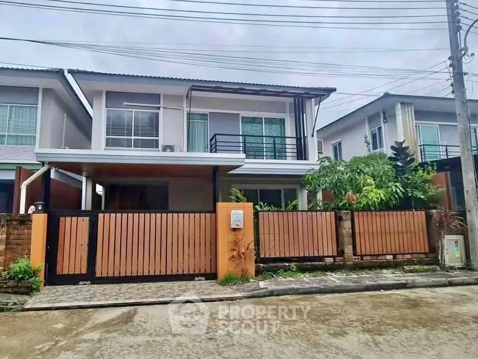 Modern two-story house with gated entrance and lush greenery