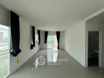 Spacious empty living room with glossy tiled floor and large windows.