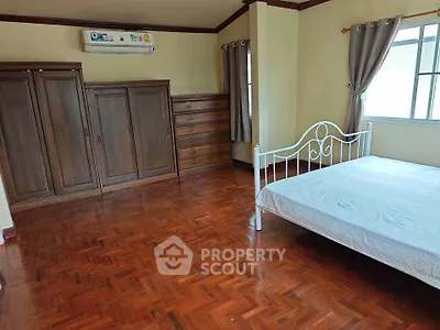 Spacious bedroom with wooden flooring and natural light