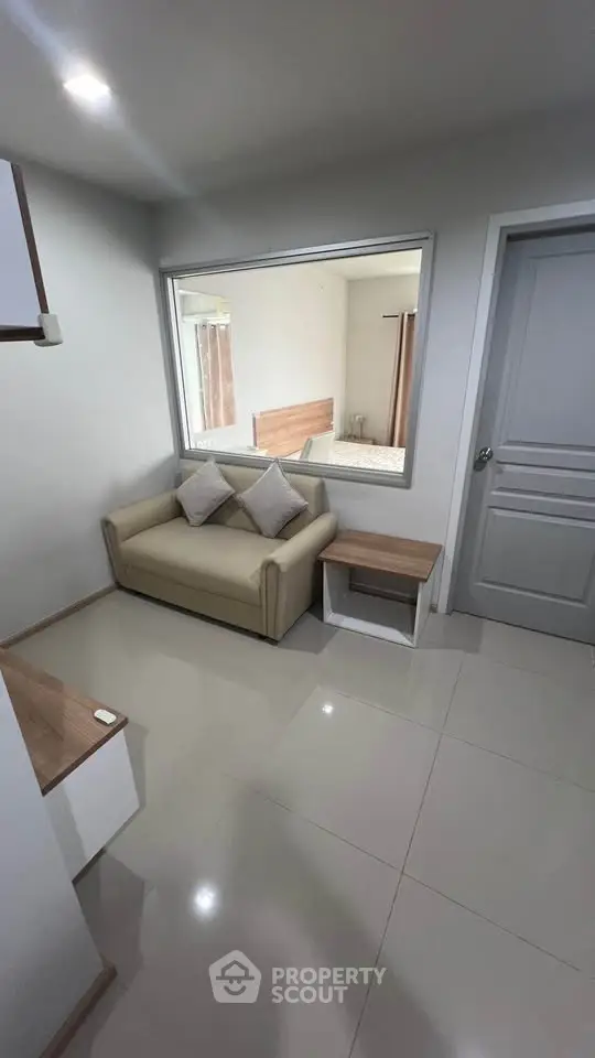 Modern living room with beige sofa and large window, showcasing minimalist design and neutral tones.