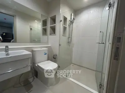 Modern bathroom with glass shower enclosure and sleek fixtures in a contemporary apartment.