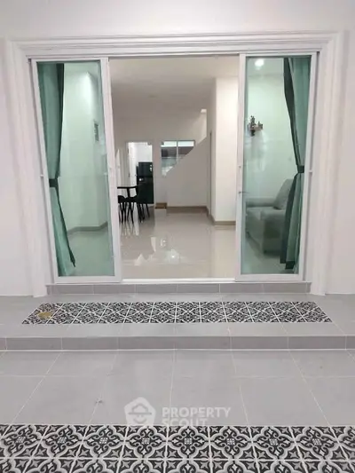 Modern interior with sliding glass doors and elegant tile flooring, leading to a spacious dining area.