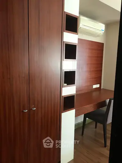 Modern study area with wooden desk and built-in storage in a cozy apartment.