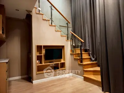 Modern duplex interior with wooden staircase and built-in TV unit