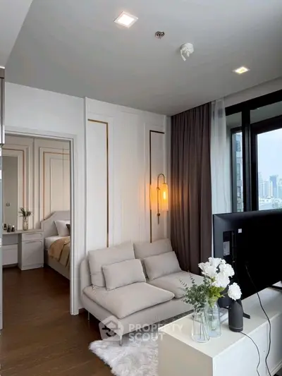 Modern living room with cozy sofa, elegant decor, and city view from large window.