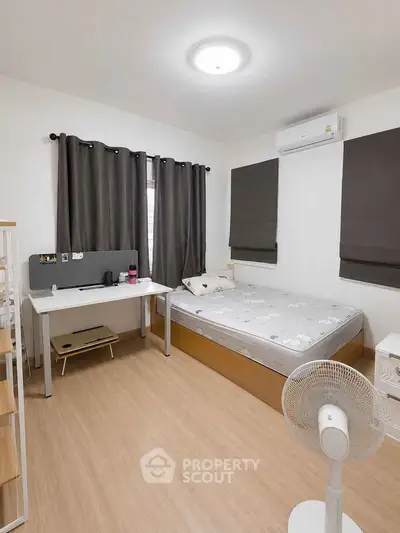 Cozy bedroom with modern decor, featuring a comfortable bed, study desk, and air conditioning.