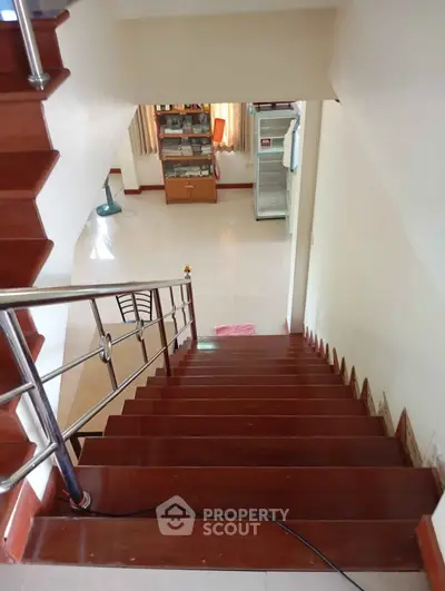 Spacious home interior with wooden staircase leading to a bright living area, showcasing modern design and open space.