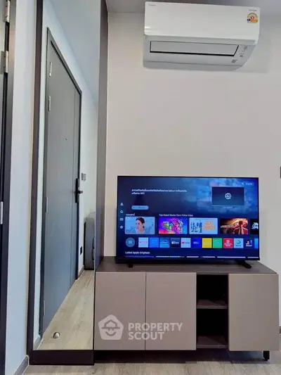 Modern living room with sleek TV setup and air conditioning unit.