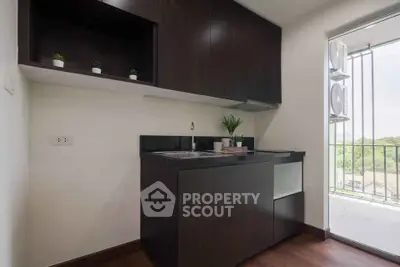Modern compact kitchen with dark wood cabinets and balcony view