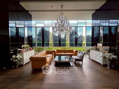 Luxurious living room with chandelier and large windows offering stunning garden views.