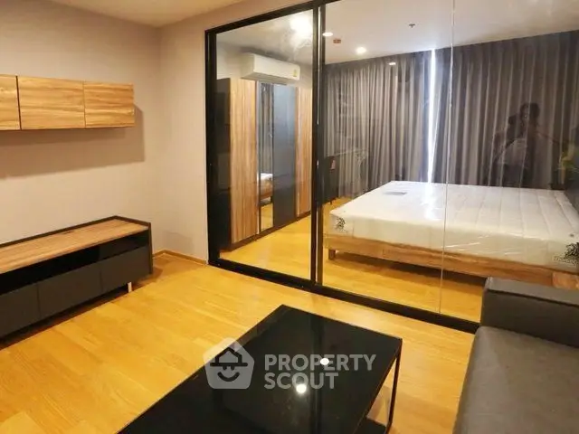 Modern apartment with glass partitioned bedroom and stylish wooden flooring.