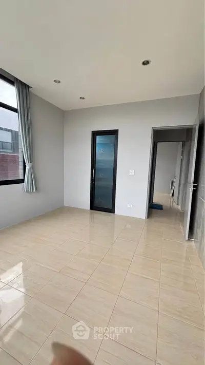 Spacious empty room with large window and modern tile flooring