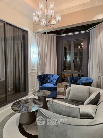 Luxurious living room with elegant blue chairs and modern chandelier, perfect for sophisticated gatherings.