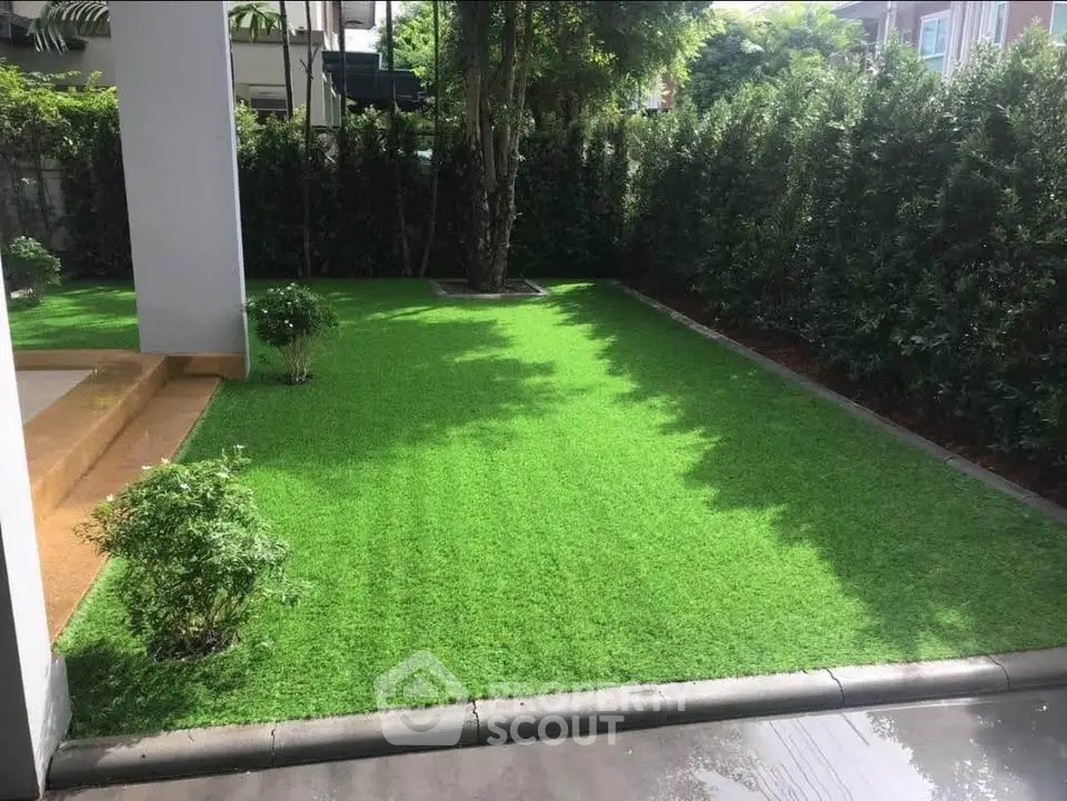 Lush green garden with manicured lawn and privacy hedges in a serene residential setting.