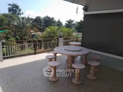 Spacious balcony with elegant stone table set and lush garden view, perfect for outdoor relaxation.