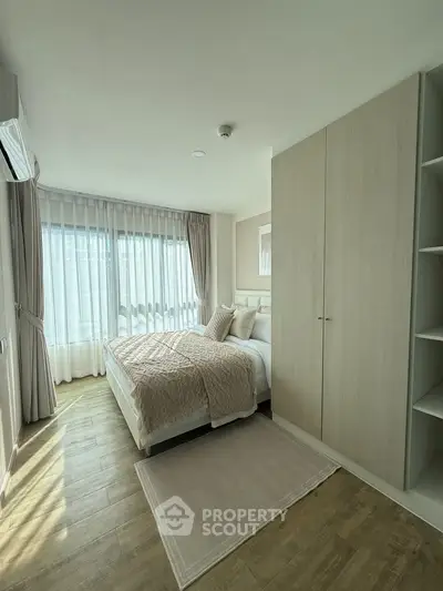 Bright and cozy bedroom with modern decor and large window for natural light.