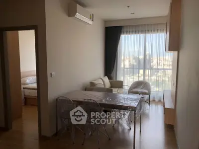 Modern living room with dining area and city view, featuring sleek furniture and natural light.