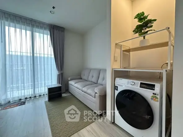 Modern living room with washing machine and cozy sofa near large window.