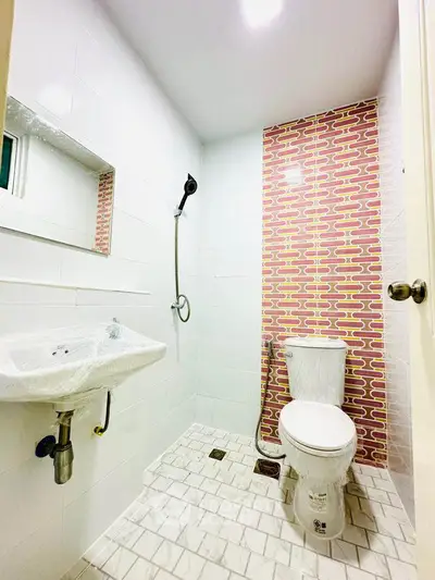Modern bathroom with stylish red brick accent wall and sleek fixtures.