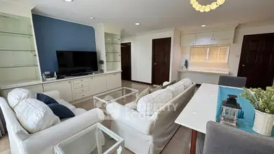 Spacious living room with elegant white sofas, glass coffee table, and built-in shelving, perfect for modern living.