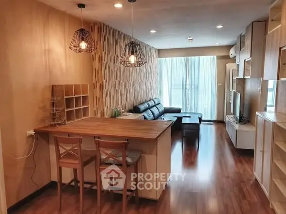 Modern living room with stylish decor and open layout, featuring a cozy seating area and wooden flooring.