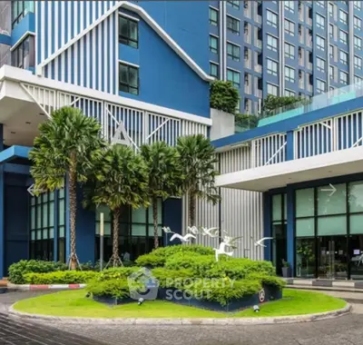 Modern blue building exterior with lush landscaping and palm trees