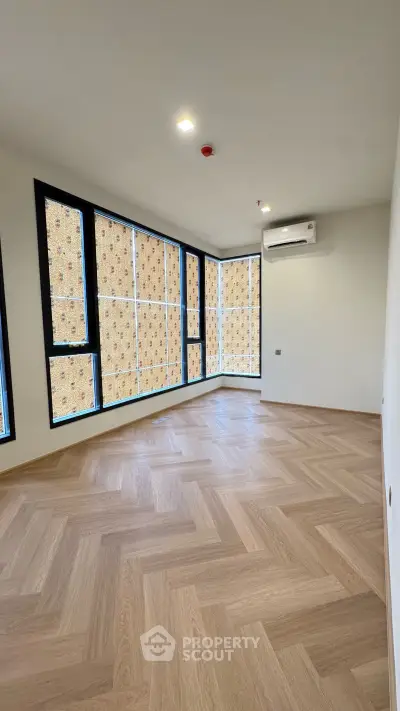 Spacious corner unit with large windows and elegant herringbone flooring, perfect for modern living.