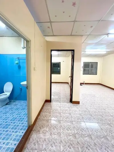 Spacious apartment interior with tiled floors and bright lighting, featuring a bathroom and open living area.