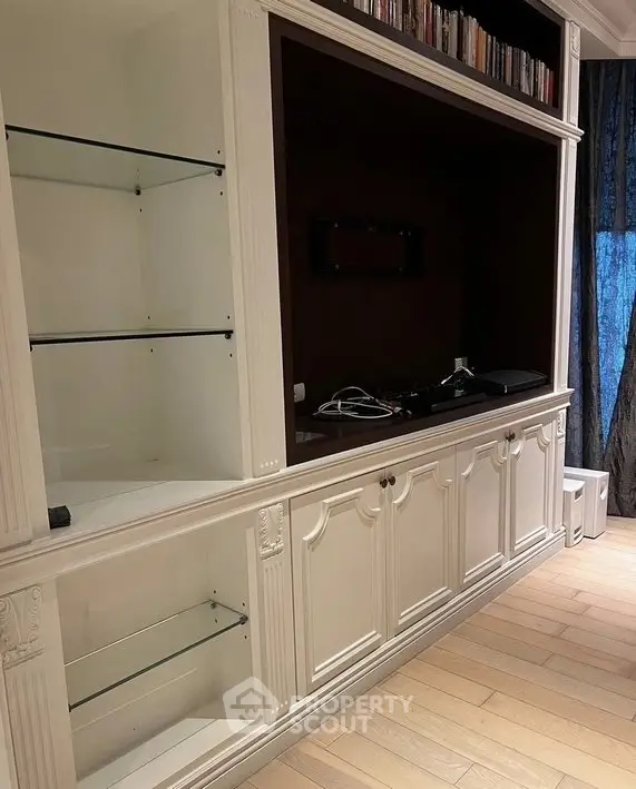 Elegant built-in shelving unit with glass shelves and wood paneling in a stylish living room.