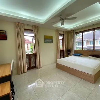 Spacious bedroom with large windows and modern decor in a serene residential area.