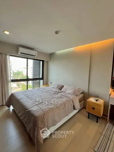 Modern bedroom with large window and cozy bedding in a high-rise apartment.