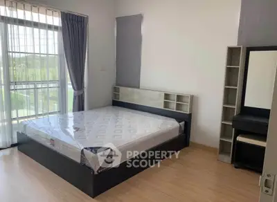 Spacious bedroom with large window and modern furnishings in a bright, airy apartment.