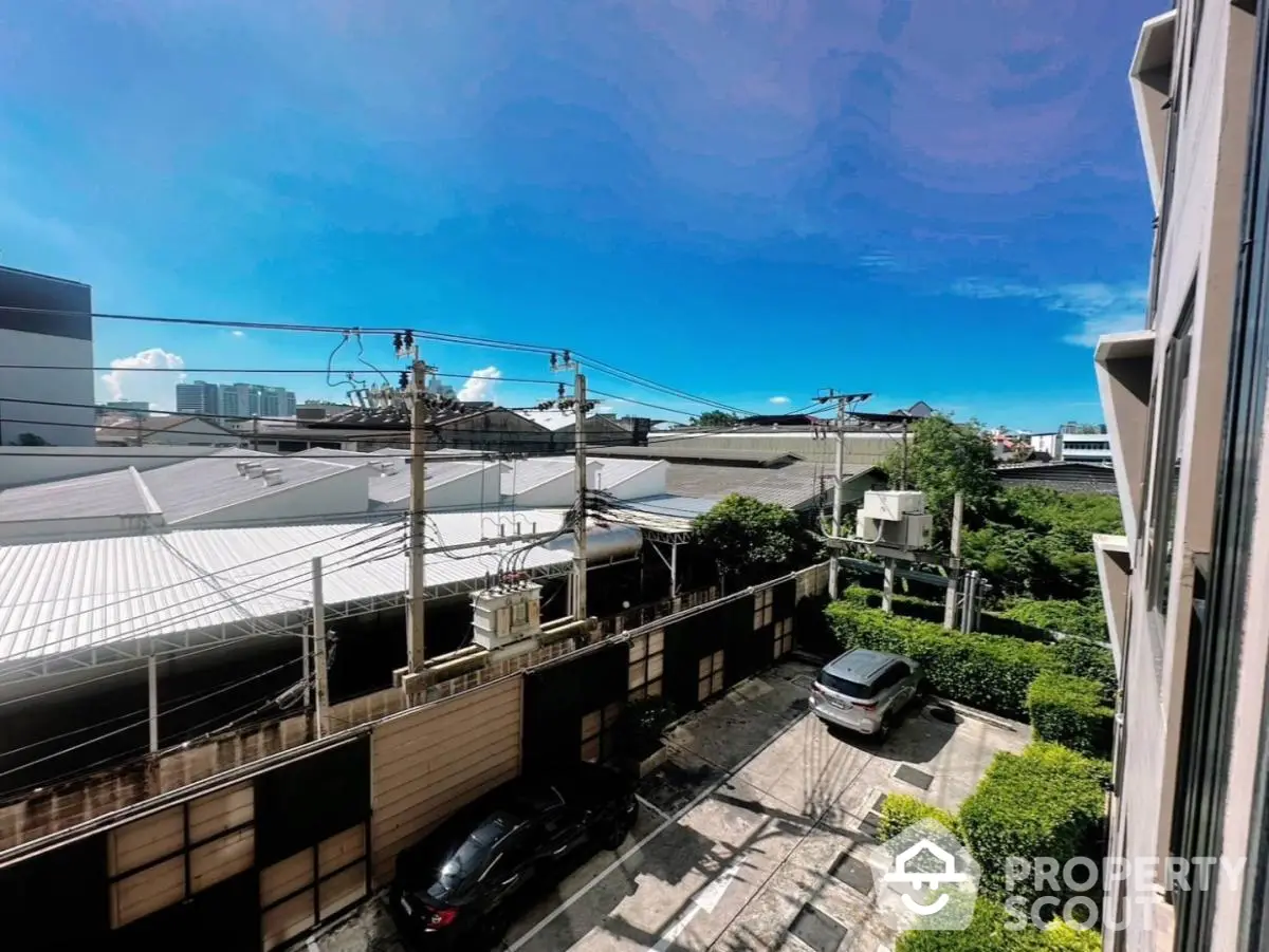 Stunning urban view from a high-rise apartment with clear blue skies and lush greenery.