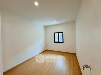 Spacious empty room with wooden flooring and bright lighting, perfect for customization.