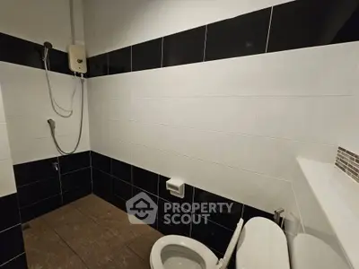 Modern bathroom with sleek black and white tiles and a shower area.