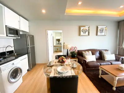 Modern open-plan living room with kitchen, featuring leather sofa and dining area.