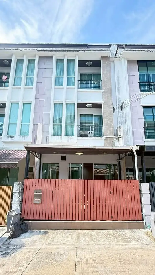 Modern three-story townhouse with gated entrance and large windows, perfect for urban living.