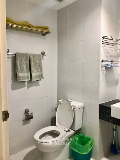Modern bathroom with sleek design, featuring a toilet, sink, and towel racks in a bright setting.