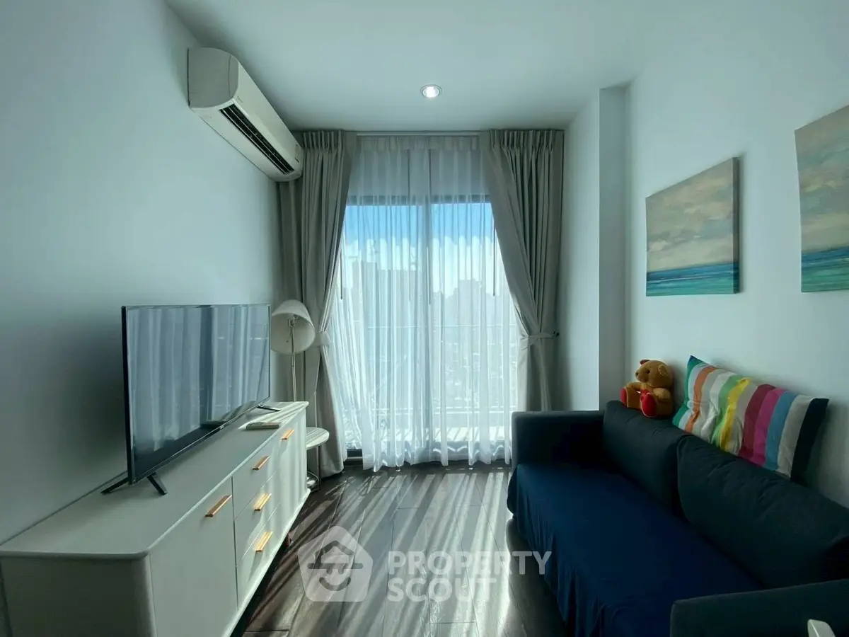 Bright living room with modern decor, large window, and cozy sofa in a stylish apartment.