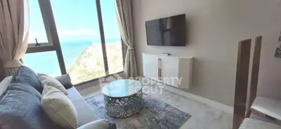 Luxurious living room with stunning ocean view, modern decor, and wall-mounted TV.