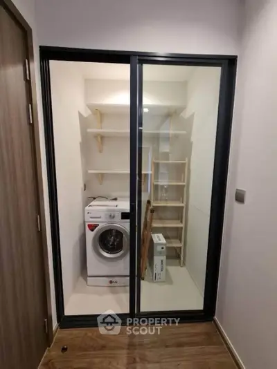 Modern storage area with washing machine and shelving in sleek apartment.