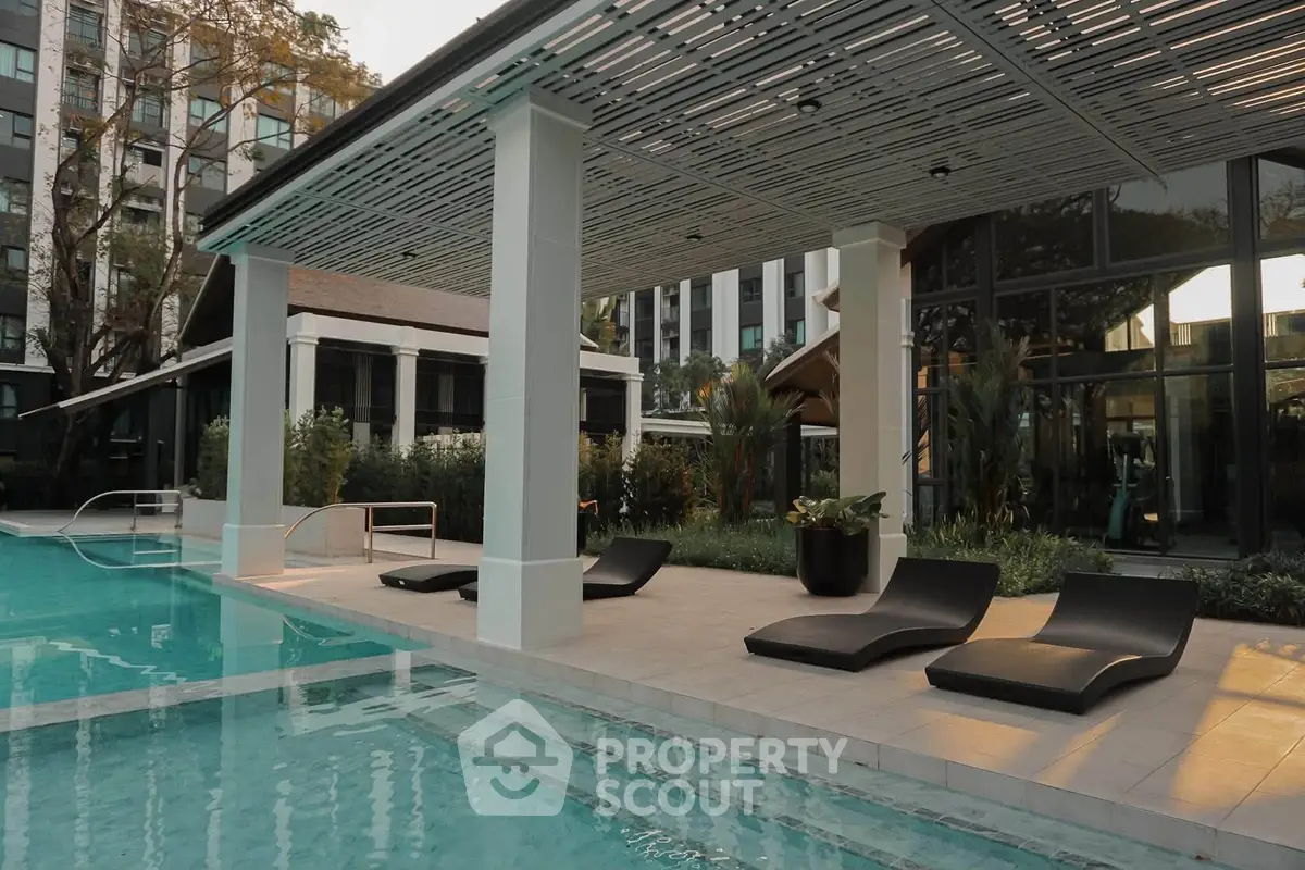 Luxurious outdoor pool area with modern lounge chairs and sleek architecture in a high-end residential complex.