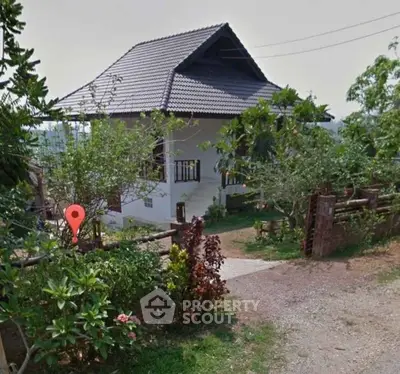 Charming countryside house with lush garden and rustic fence, perfect for serene living.