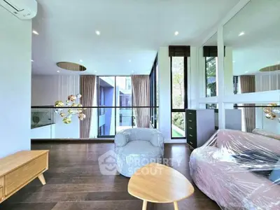 Modern living room with stylish furniture and large windows offering natural light and garden view.