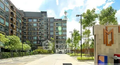 Modern apartment building with lush greenery and spacious parking area.